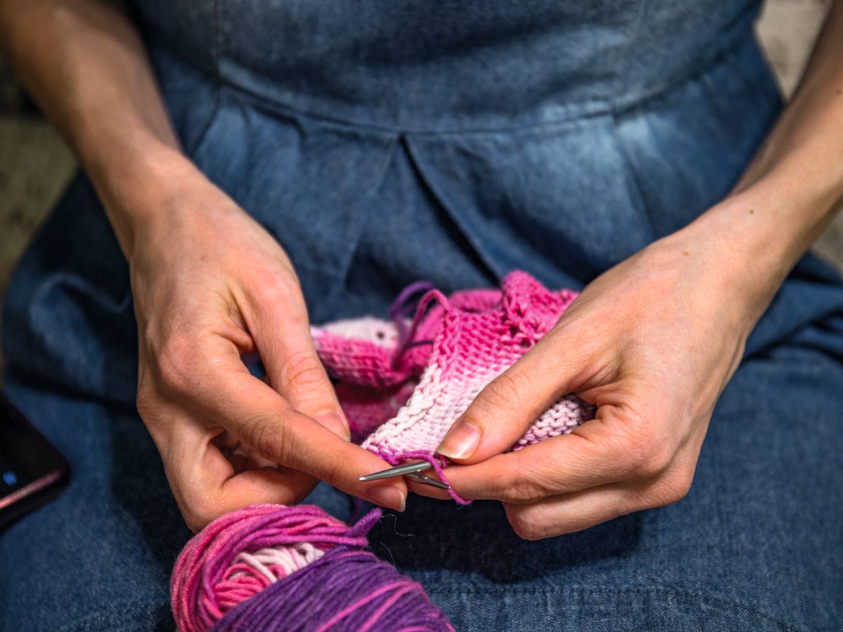 Mensch strickt mit bunter Wolle 
