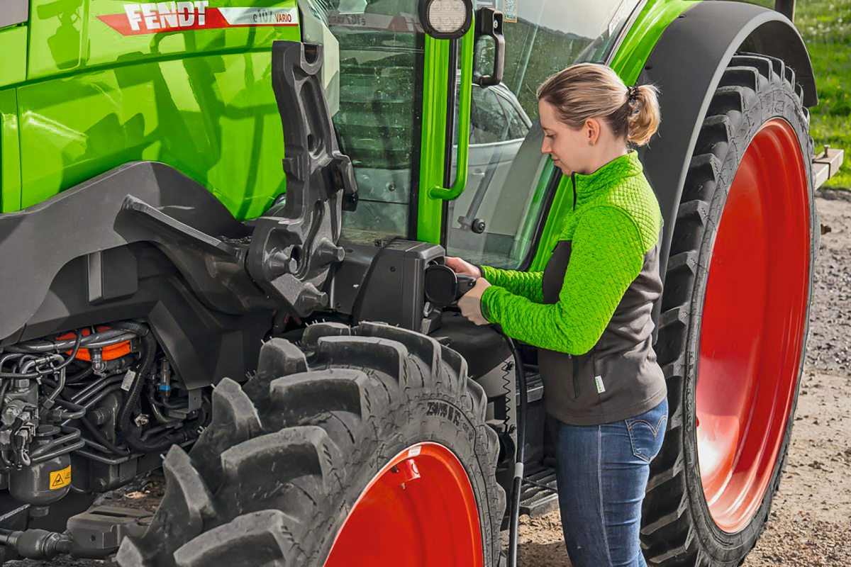 Landwirtin steht neben einem Fendttraktor