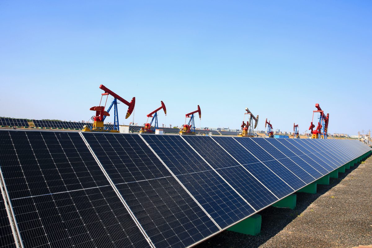 Solarpanele auf einer Fläche, dazwischen Ölpumpen