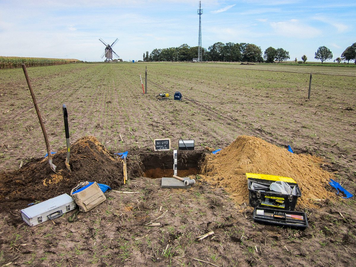 Ein Acker mit einem ausgehobenen Bodenprofil und den nötigen Utensilien