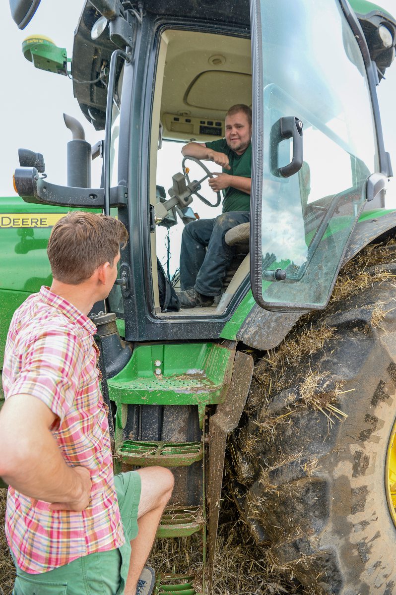 Zwei Landwirte unterhalten sich, einer sitzt auf einem Traktor