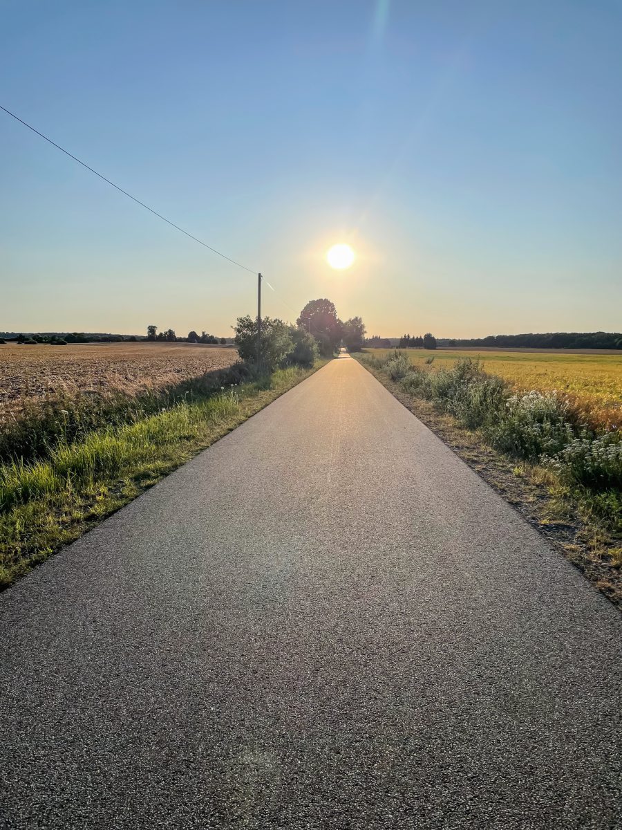Straße auf dem Land mit Soonnenuntergang im Hintergrund