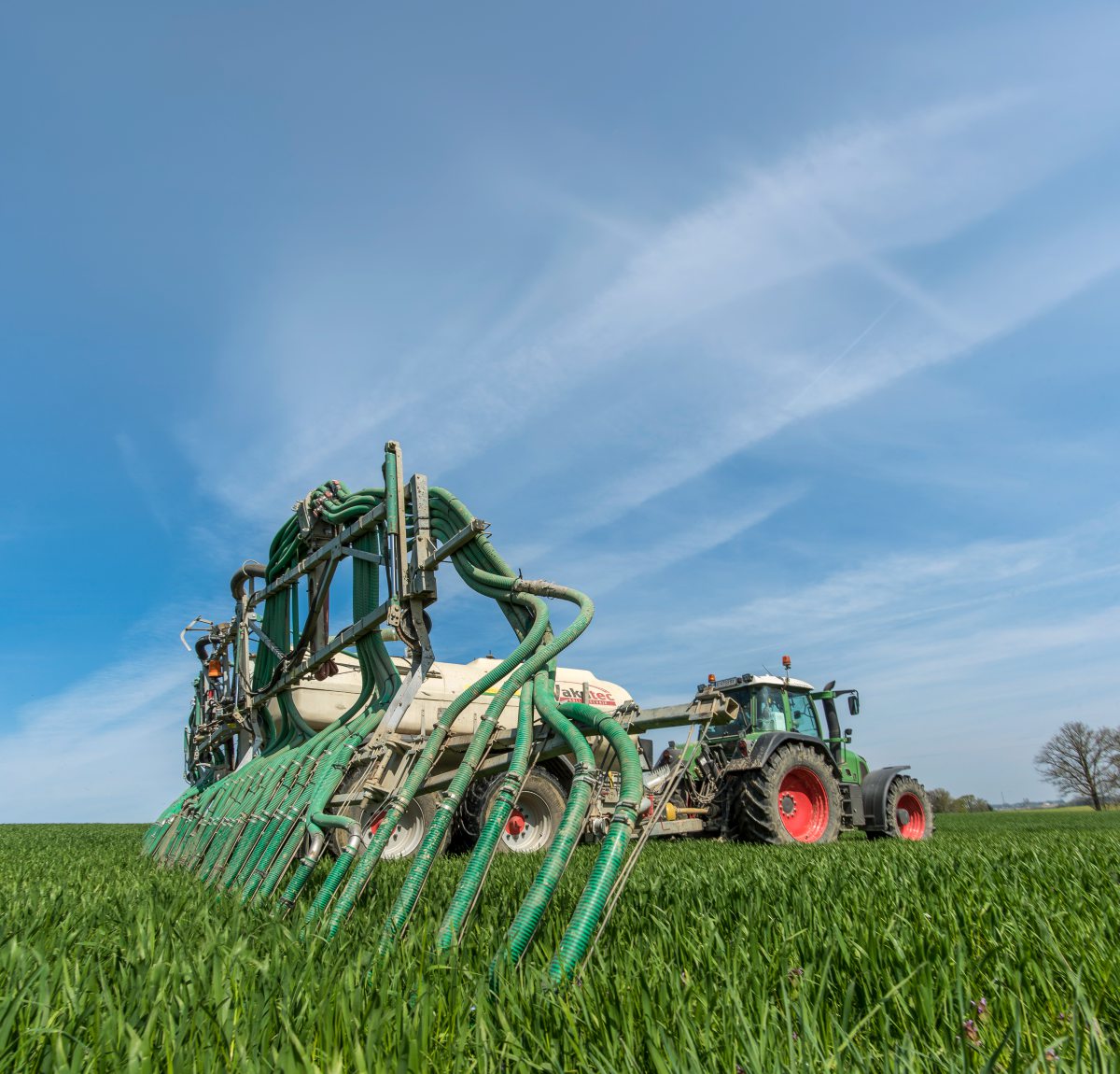 Traktor mit angehängtem Gülletank auf Feld