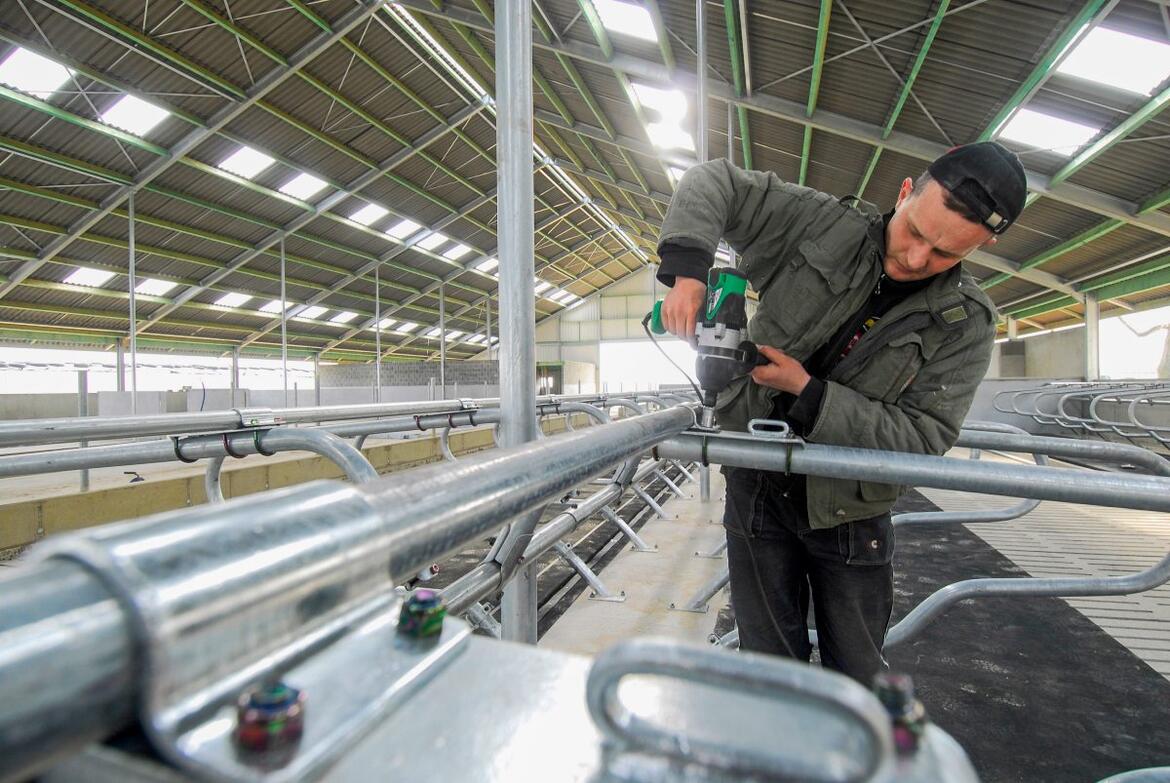 Landwirt montiert Stalleinrichtung in einem Milchviehstall
