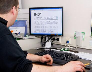 Landwirt sitzt im Stallbüro vor dem Computer