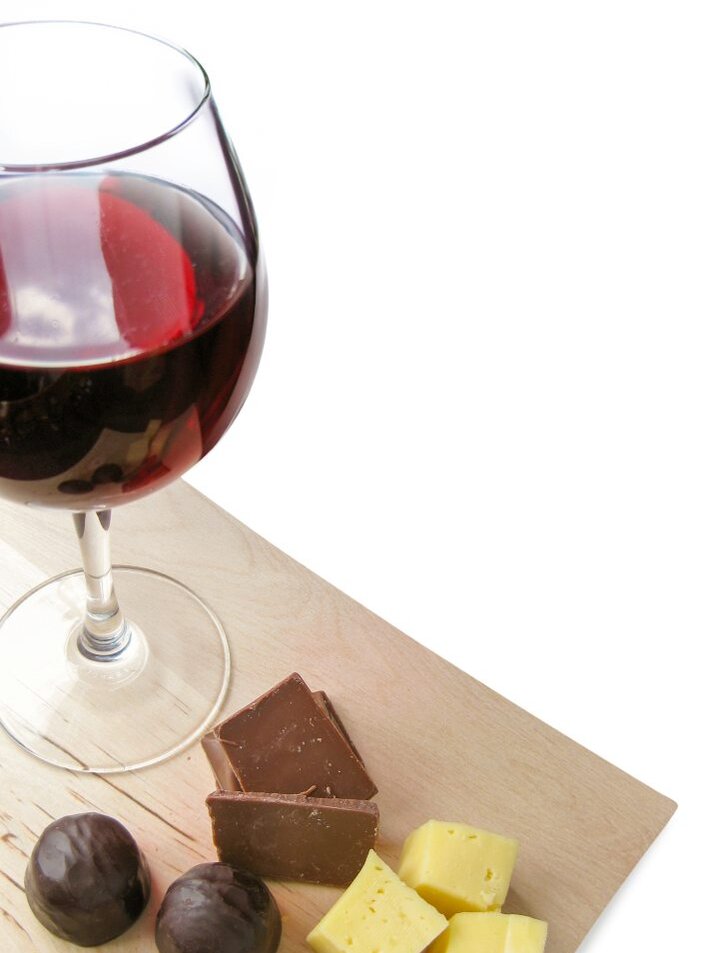 Wein, Trauben, Schokolade und Käse auf einem Holzbrett
