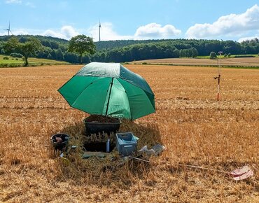 Ein Bodenprofil auf einem Acker mit einem Schirm abgedeckt