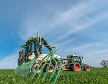 Traktor mit angehängtem Gülletank auf Feld