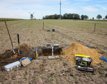 Ein Acker mit einem ausgehobenen Bodenprofil und den nötigen Utensilien