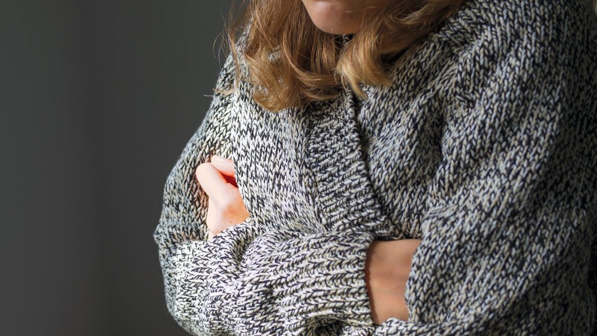 fröstelnde Frau in Strickpulli