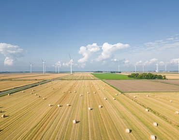 Abgeerntetes Getreidefeld mit Windkraftanlagen in Nordfriesland, Deutschland 