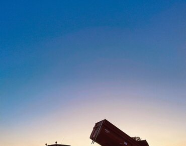 Kipplader mit Getreide im Sonnenuntergang